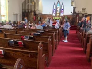 group of people sitting in pews at a church with red carpet